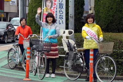 おかざき候補（右端）と自転車で町中を宣伝する梅村衆院議員（その隣）＝2015年3月21日、戸田市